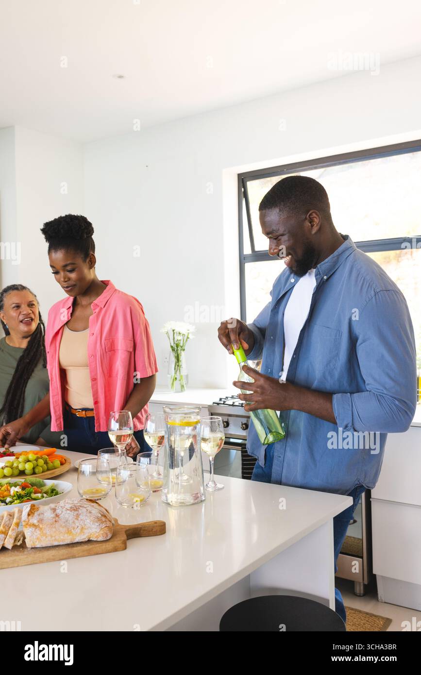 Gli amici preparano bevande e si divertono a conversare in una cucina moderna e luminosa. Socializzare, amicizia, stile di vita, cucina, bevande, informale Foto Stock