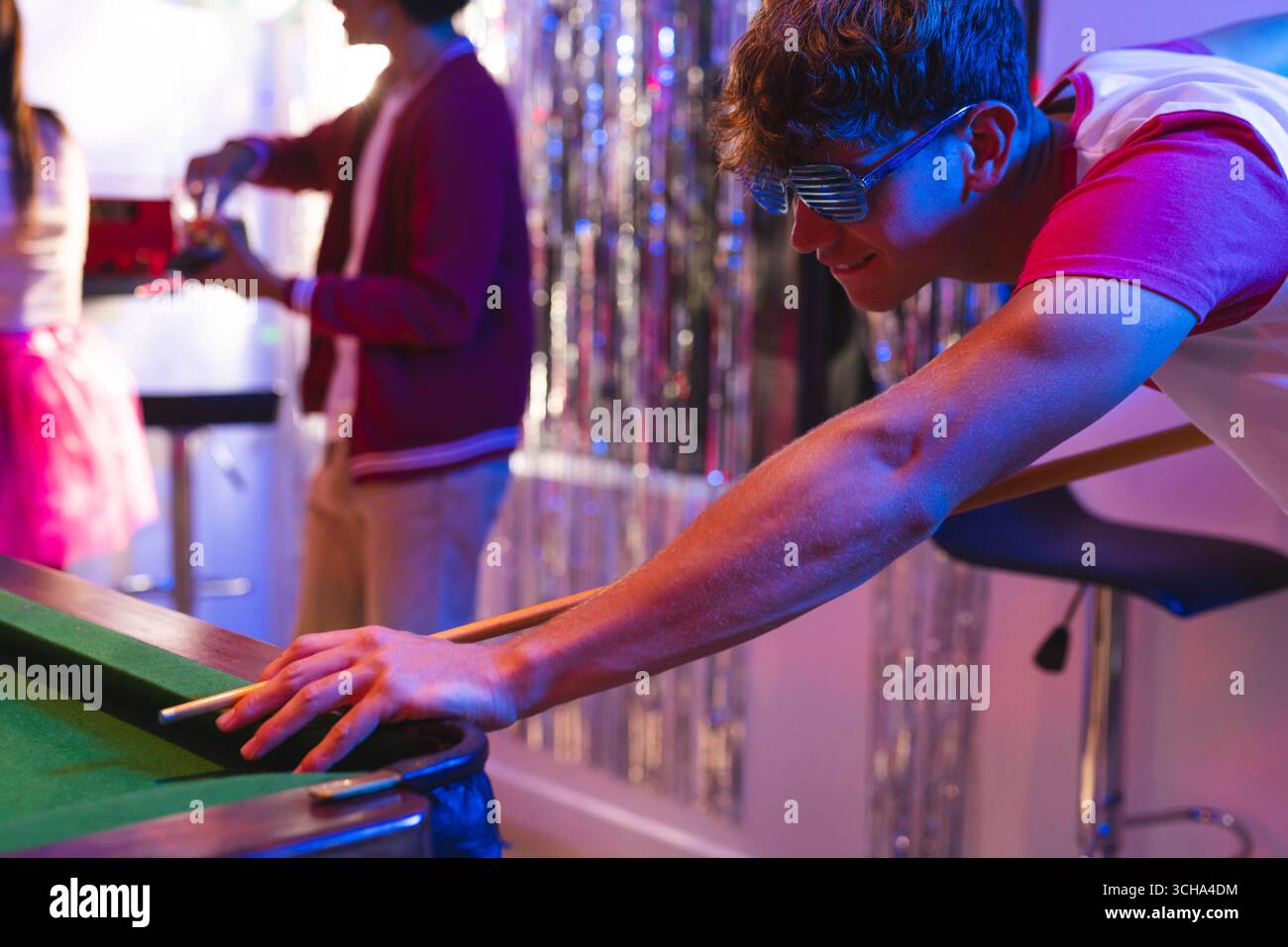 Adolescenti che giocano a biliardo alla festa, indossano occhiali da sole, si divertono a festeggiare a casa. Adolescente, biliardo, tempo libero, riunione Foto Stock