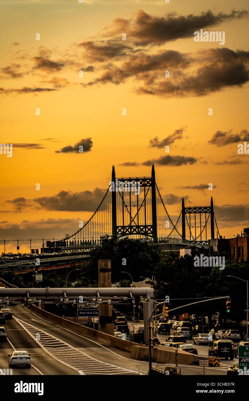 Il cielo della sera d'oro illumina un ponte sospeso e la trafficata strada di avvicinamento a New York City. Foto Stock