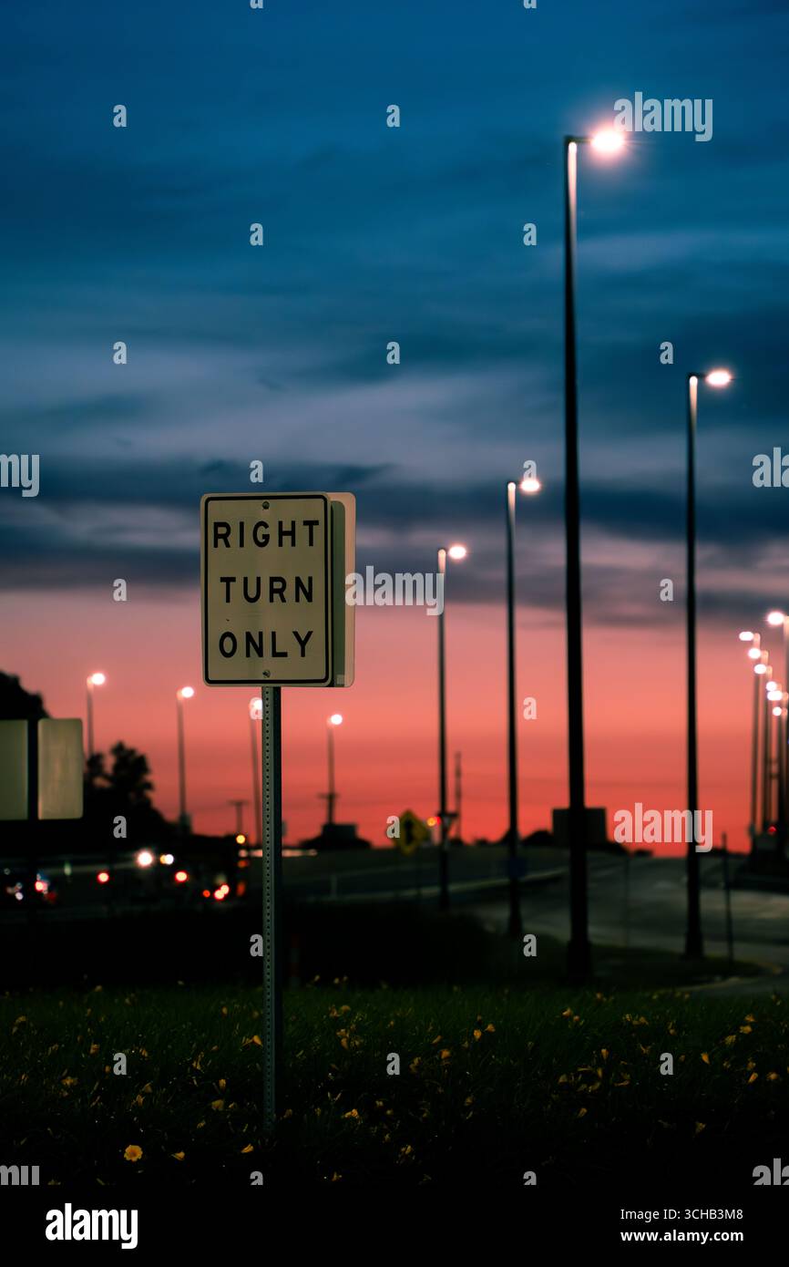 Cartello stradale "Right Turn Only" (solo svolta a destra) con semafori al tramonto. Foto Stock