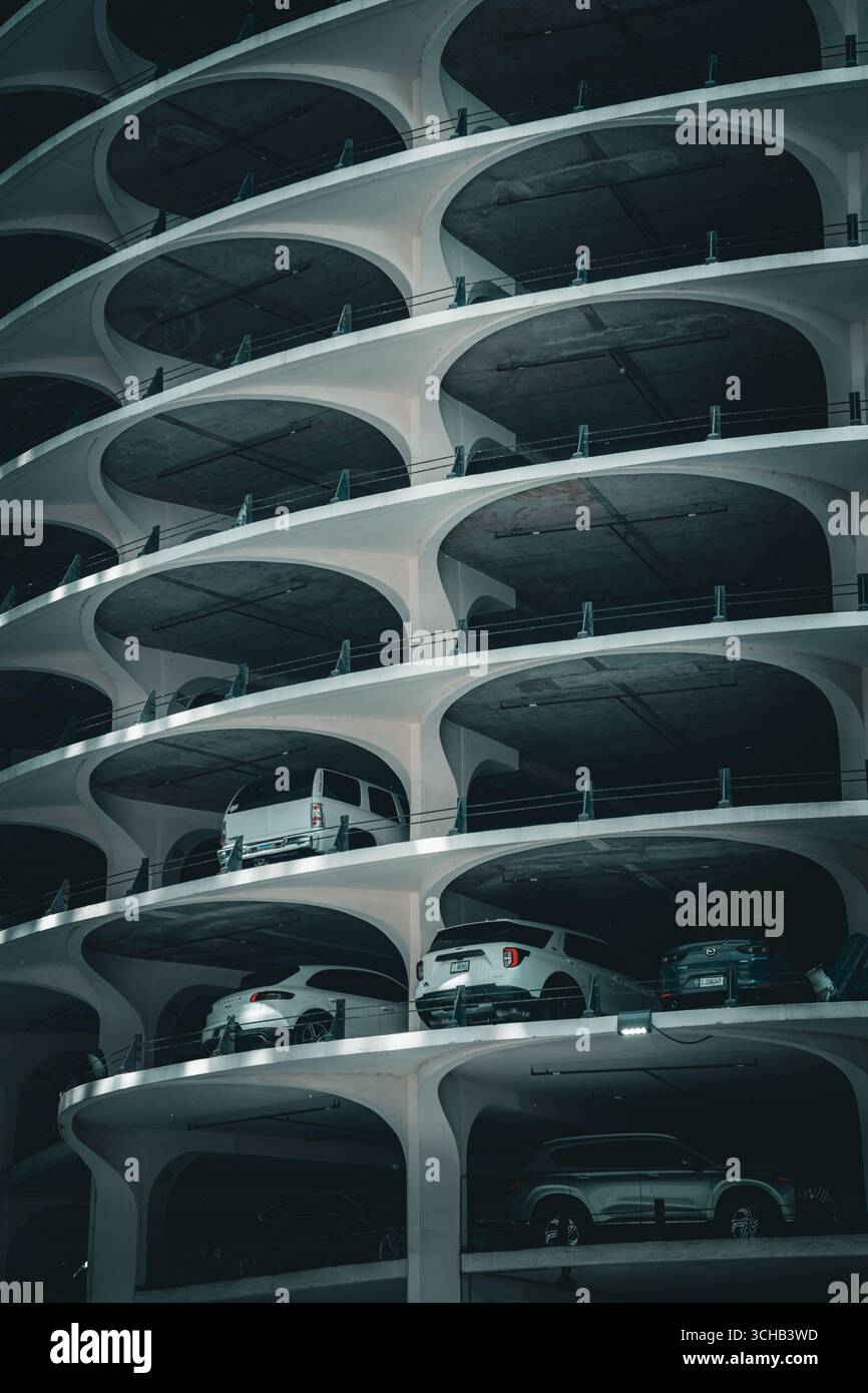 Parcheggio a spirale con auto parcheggiate su più livelli, che mostra una ripetizione architettonica e un design urbano. Foto Stock