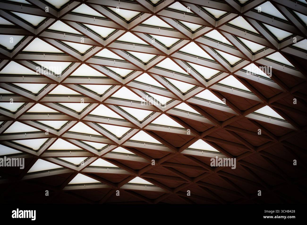 Design geometrico del soffitto con ripetuti motivi a forma di diamante che creano simmetria e contrasto di luce nell'aeroporto di Incheon. Foto Stock