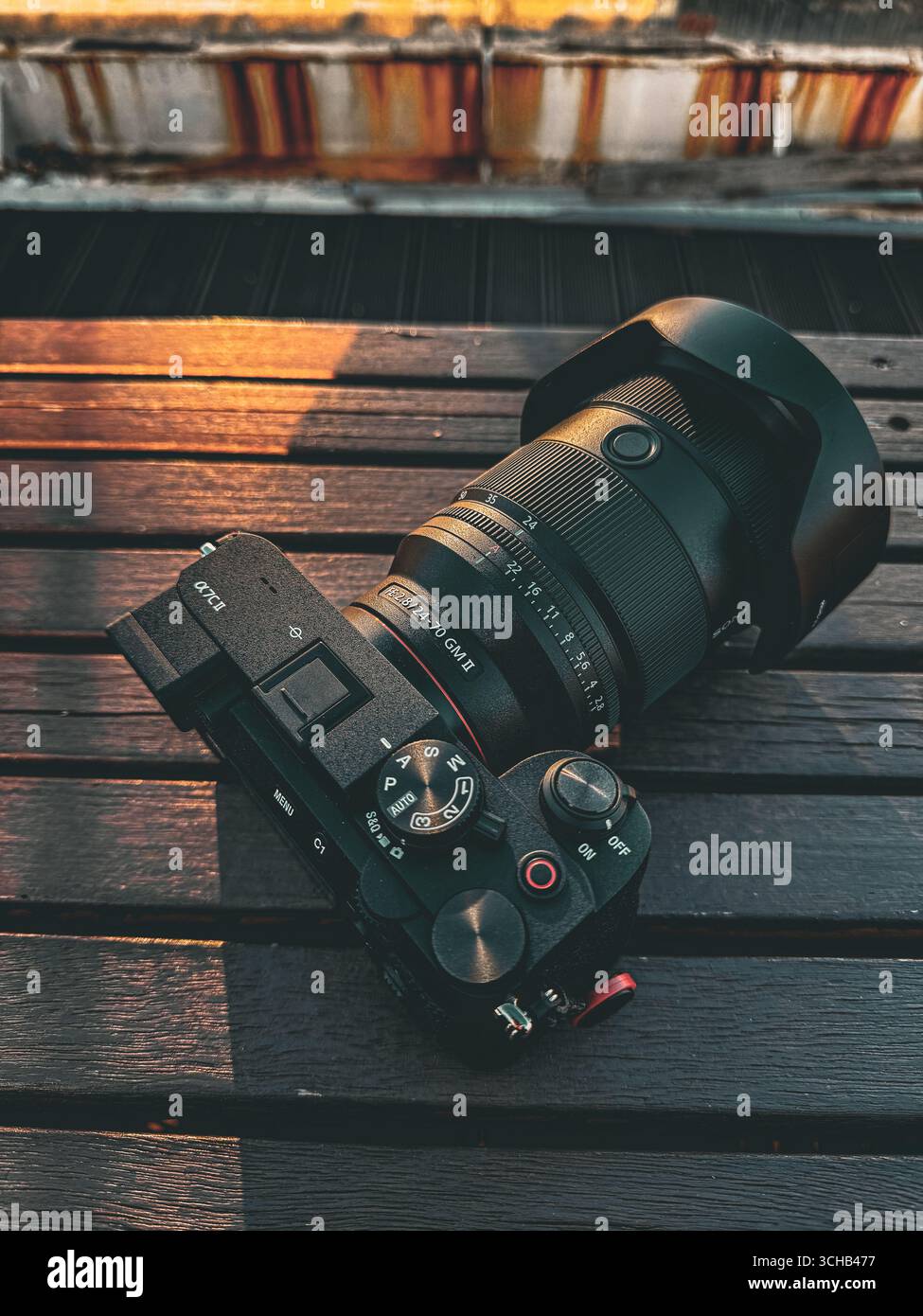 Fotocamera Sony Alpha con obiettivo GM II da 70 mm posizionato su una superficie in legno sotto la calda luce del sole. Foto Stock
