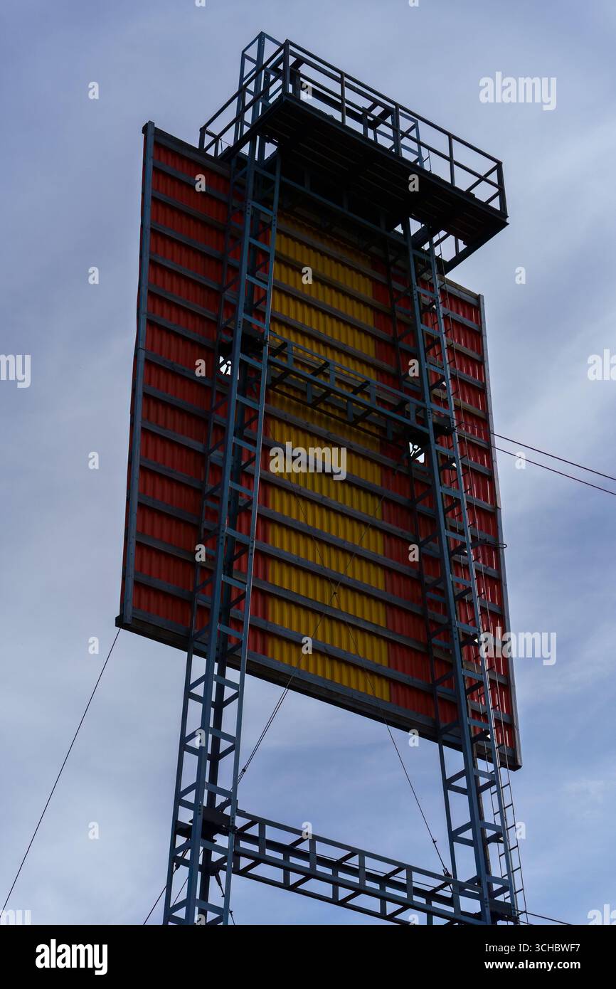 Close up of a red and yellow sea marker standing on land against a clear blue sky Foto Stock