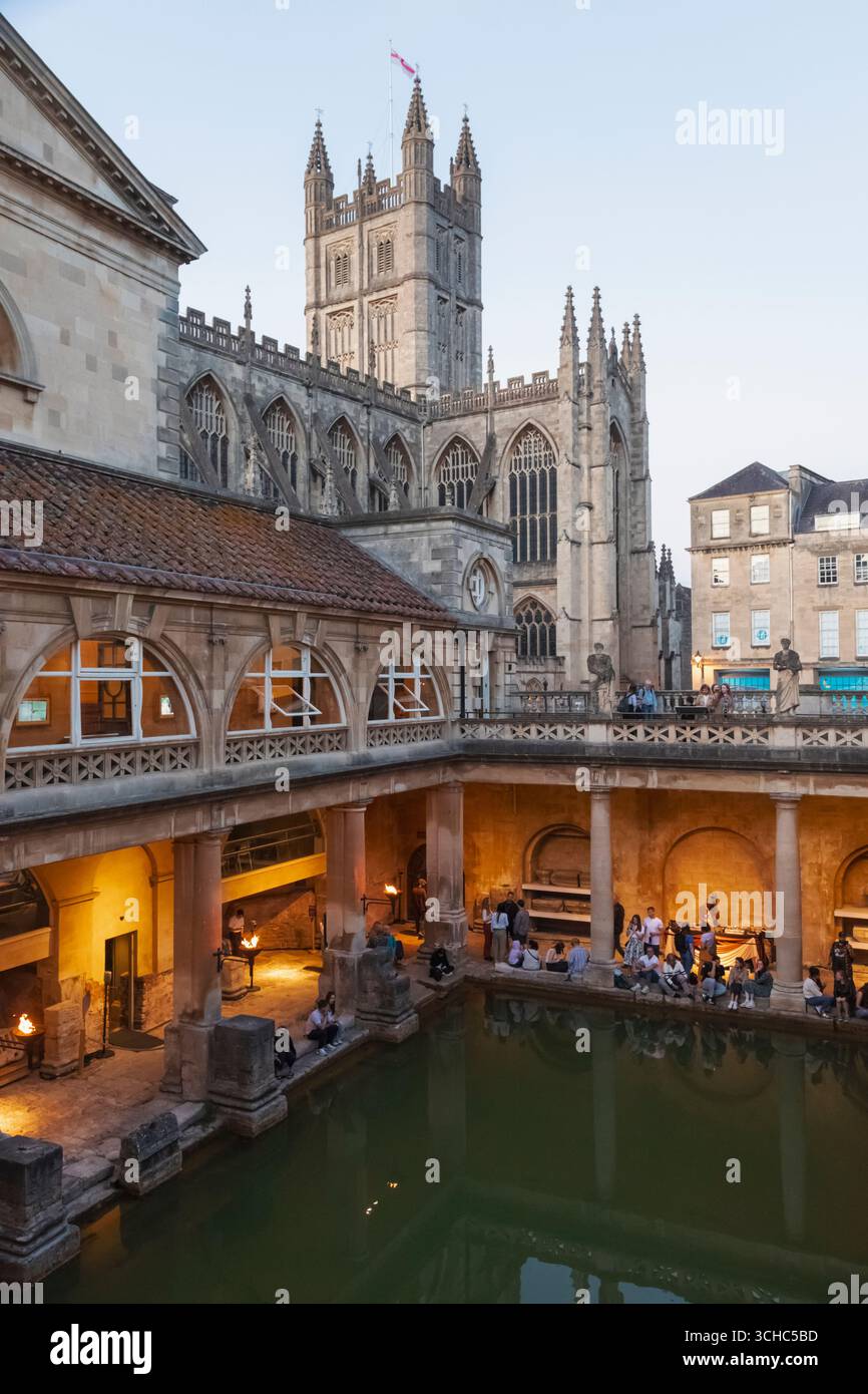 Inghilterra, Somerset, Bath, le terme romane illuminate di notte con l'Abbazia di Bath sullo sfondo Foto Stock