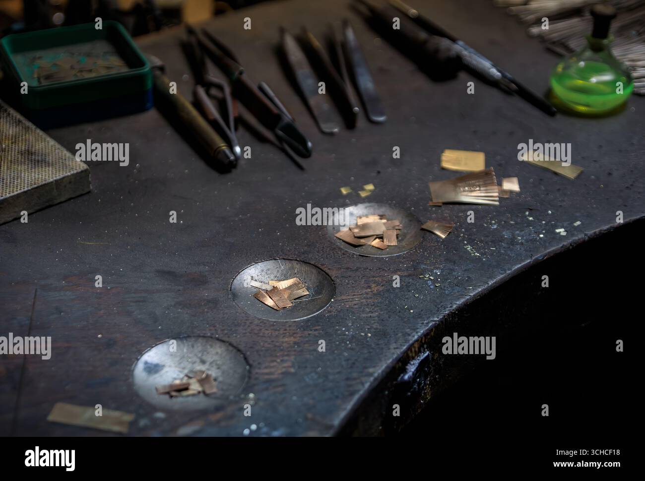 Un banco da lavoro per gioiellieri pieno di utensili e materiali specializzati per la lavorazione dei metalli, punte per trapano in metallo e una bottiglia di acido per gioiellieri a Zurigo, Svizzera Foto Stock