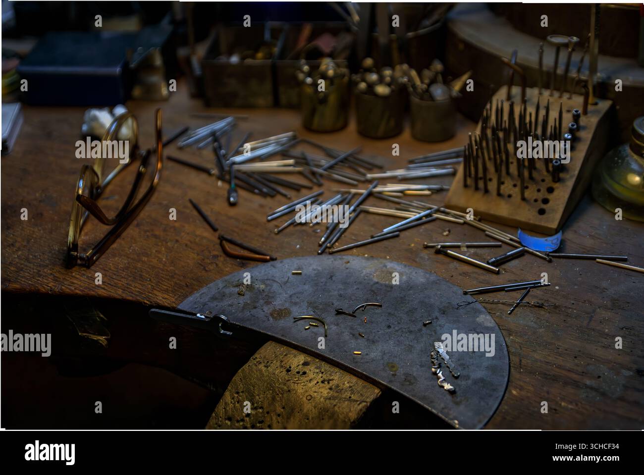 Un banco da lavoro per gioiellieri pieno di utensili e materiali specializzati per la lavorazione dei metalli, punte per trapano in metallo e una bottiglia di acido per gioiellieri a Zurigo, Svizzera Foto Stock