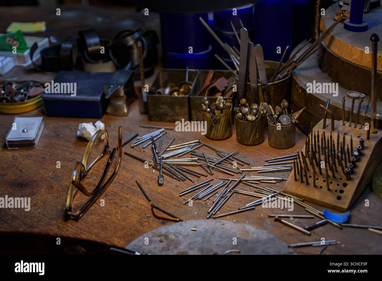 Un banco da lavoro per gioiellieri pieno di utensili e materiali specializzati per la lavorazione dei metalli, punte per trapano in metallo e una bottiglia di acido per gioiellieri a Zurigo, Svizzera Foto Stock