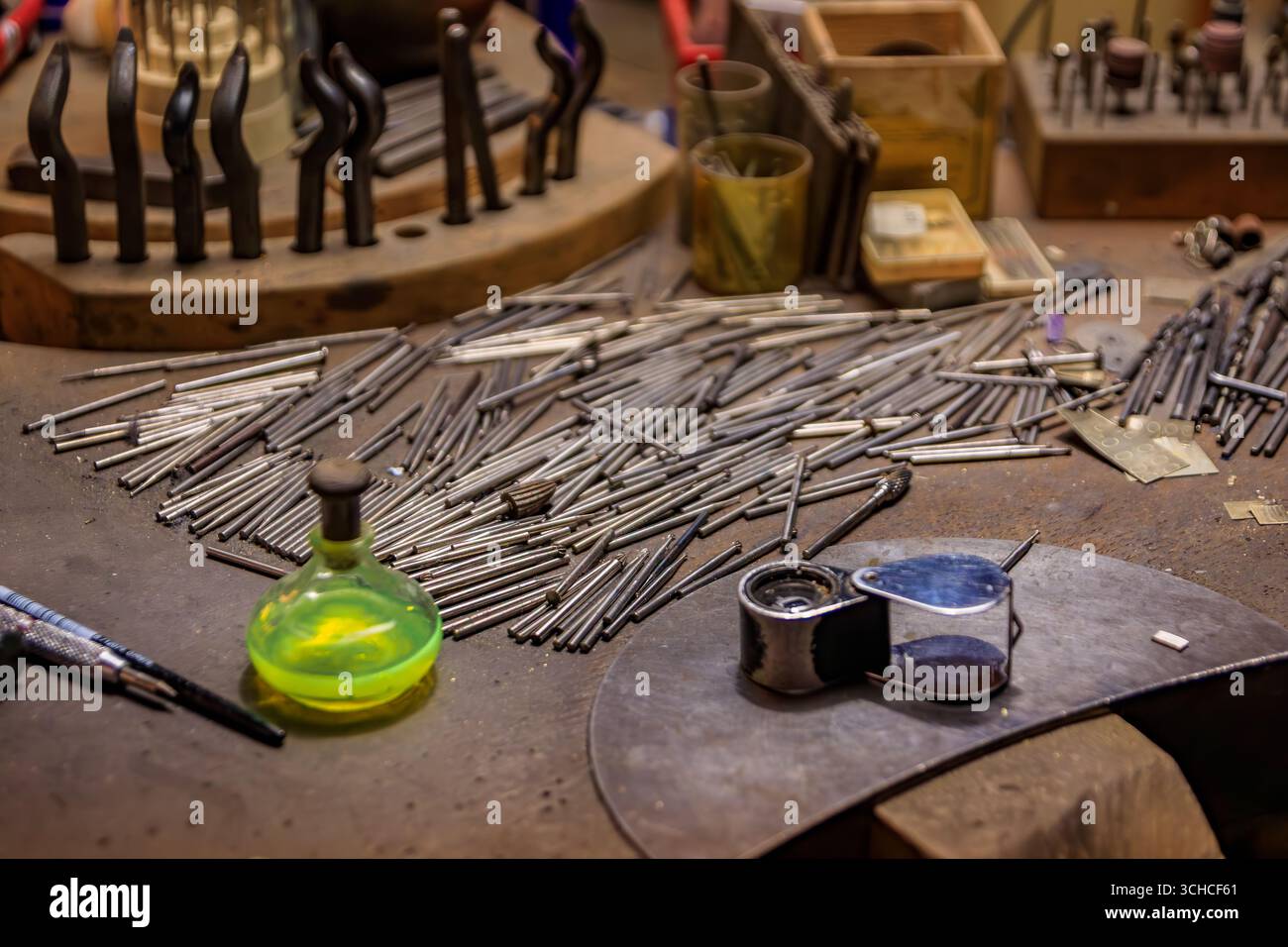 Un banco da lavoro per gioiellieri pieno di utensili e materiali specializzati per la lavorazione dei metalli, punte per trapano in metallo e una bottiglia di acido per gioiellieri a Zurigo, Svizzera Foto Stock