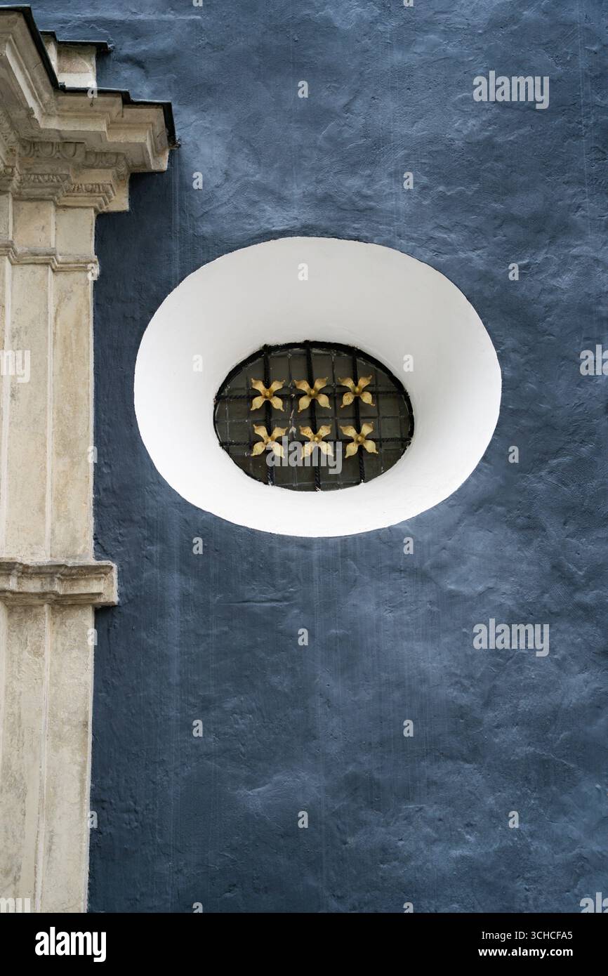 Storica parete blu della chiesa con finestra ovale decorativa e colonna di pietra ornata a Tallinn in Estonia Foto Stock