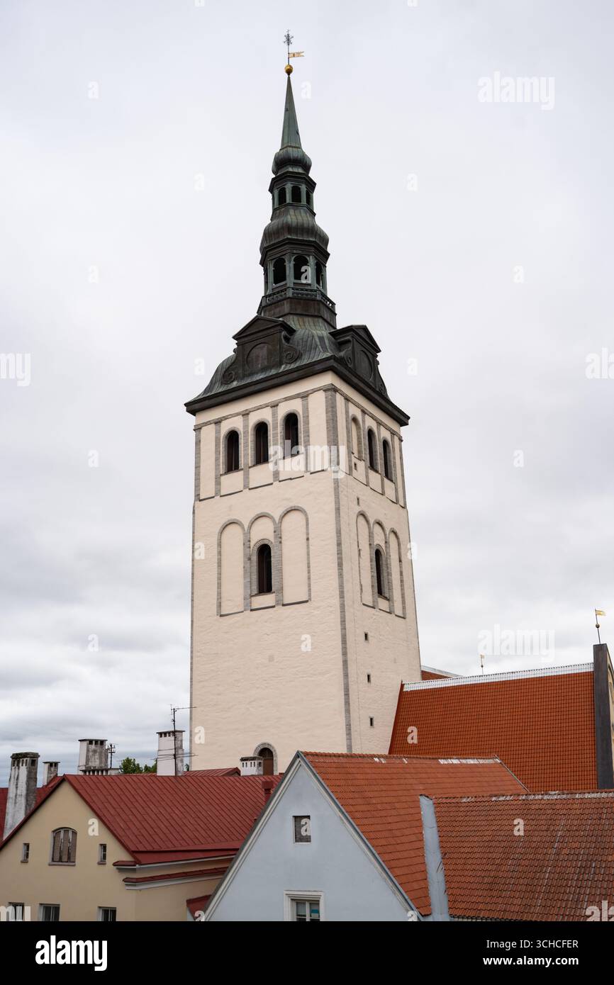 Storica torre della chiesa con guglie verdi di rame che si innalzano sopra i tradizionali tetti di tegole rosse nella città vecchia di Tallinn Foto Stock