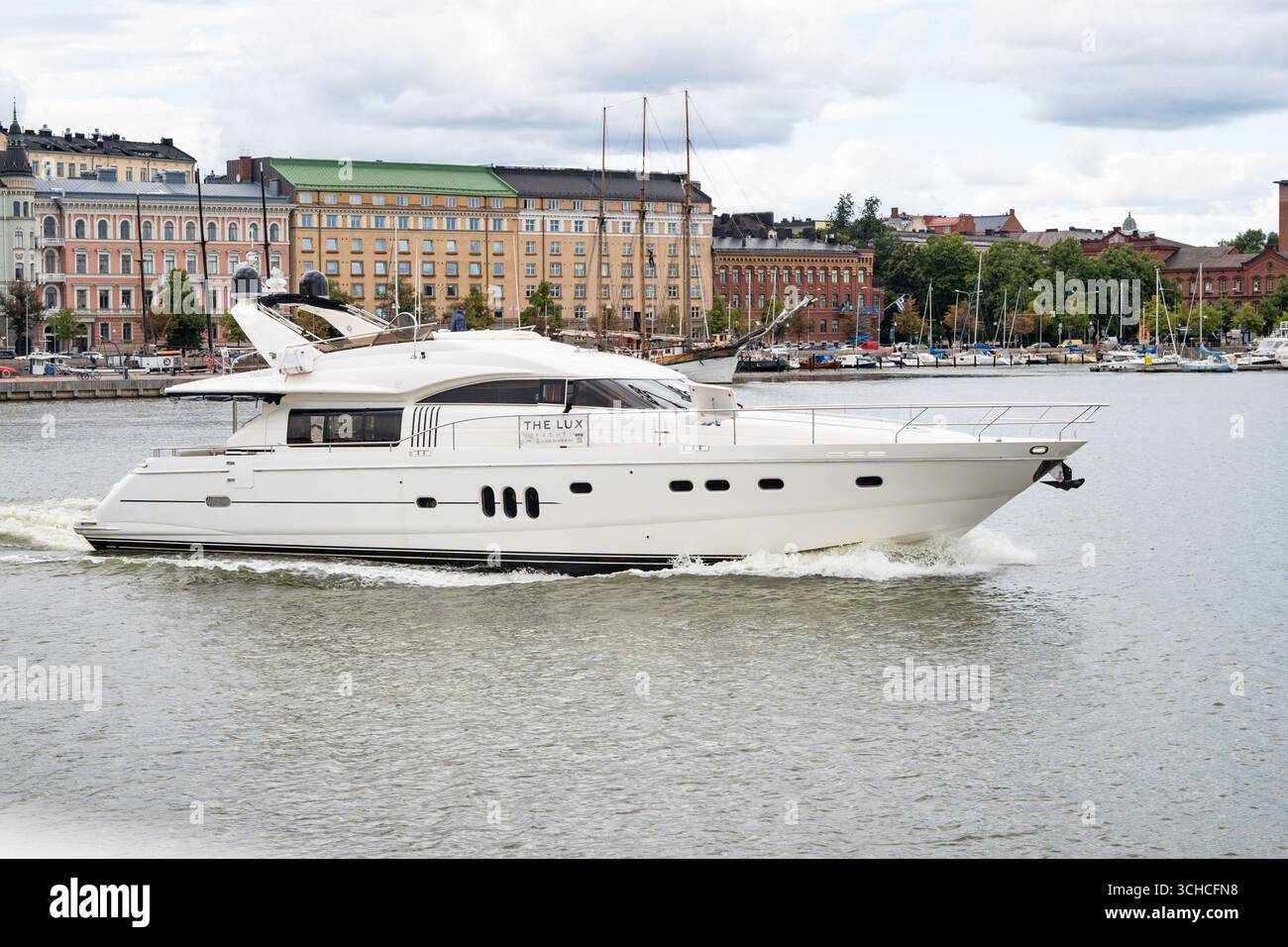 Yacht di lusso bianco che passa davanti allo storico lungomare di Helsinki con edifici colorati e porticciolo Foto Stock