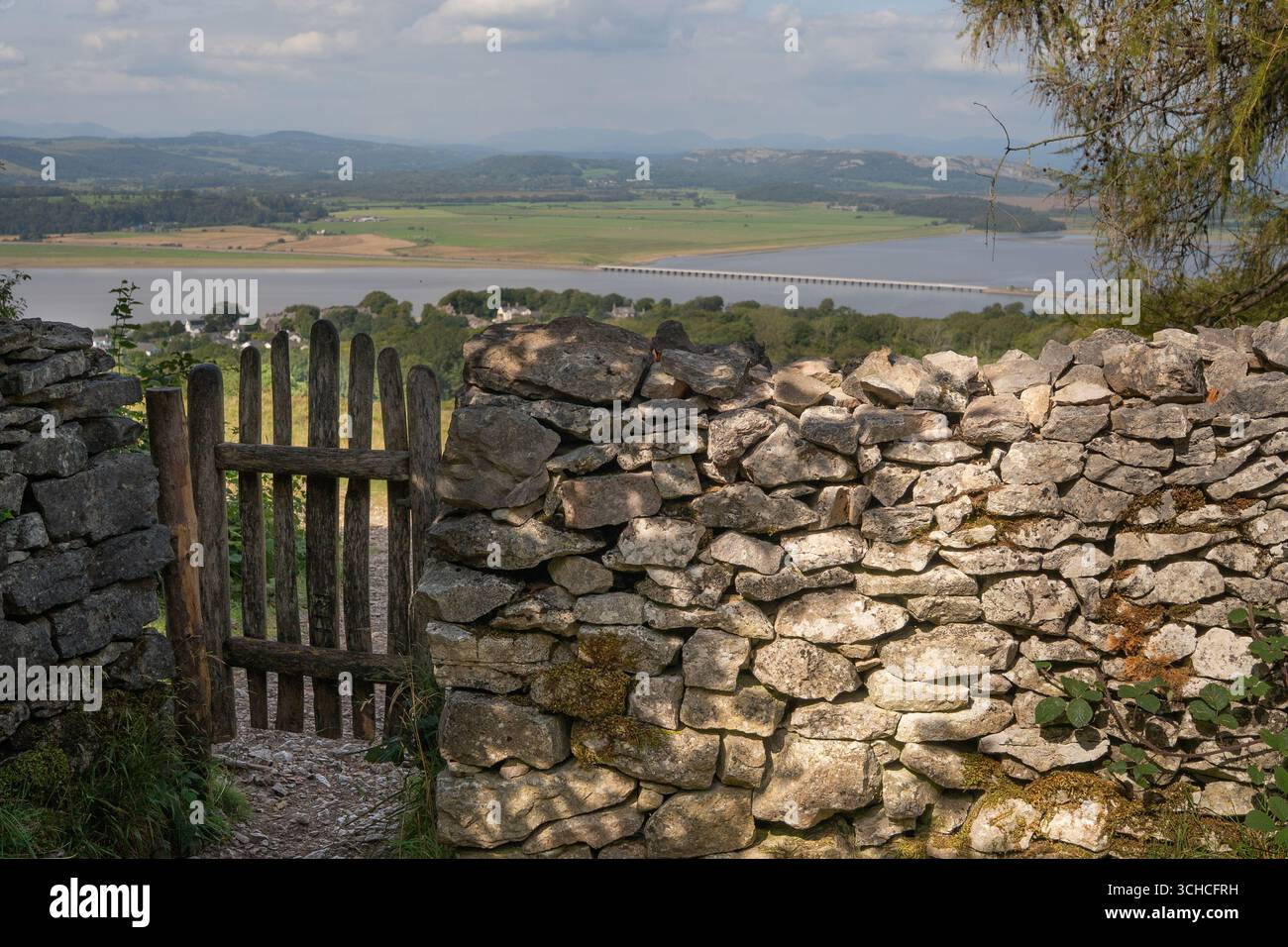 Tradizionale muro di pietra a secco e cancello di legno che si affaccia sulla campagna con viadotto ferroviario Foto Stock