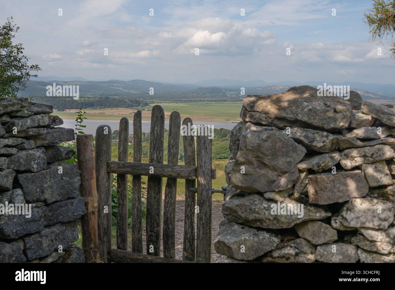 Cancello in legno rustico e muro in pietra a secco che si affaccia sulla valle della campagna e sulle colline lontane Foto Stock