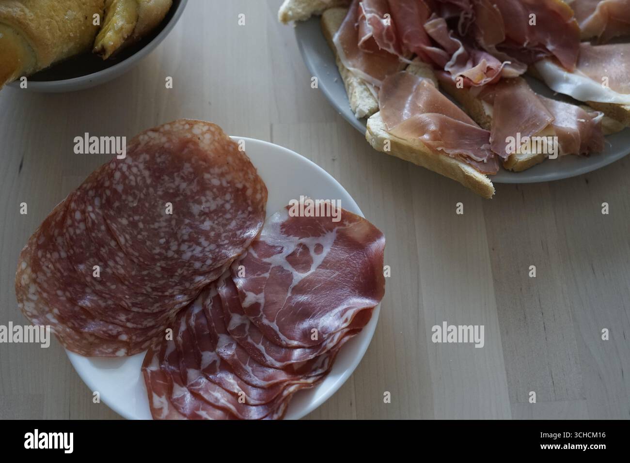 Un delizioso assortimento di salumi esposti ad arte su un tavolo di legno Foto Stock