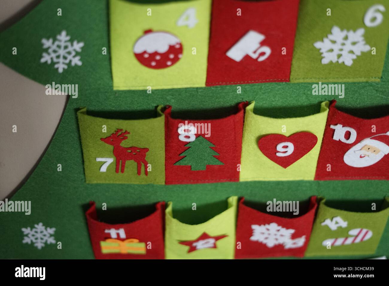 Un vivace calendario dell'Avvento in feltro progettato come albero di Natale, con tasche colorate adornate con simboli festivi come fiocchi di neve, ornamenti e Foto Stock