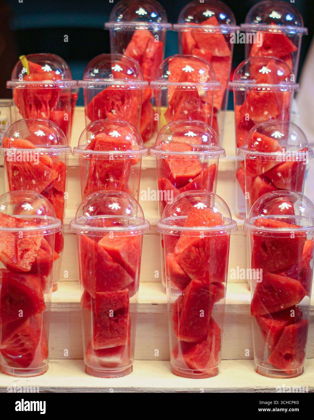 Bicchieri in plastica trasparente riempiti di cubetti di anguria, sigillati con coperchi a cupola. Popolare frutta di strada tailandese per succhi, frullati e spuntini salutari. Foto Stock