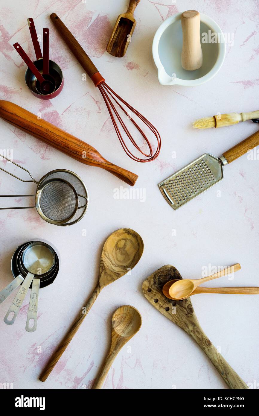 Una collezione piatta di vari utensili da forno rustici e moderni, tra cui una frusta, un mattarello, una grattugia e cucchiai di legno, uscita impostata Foto Stock