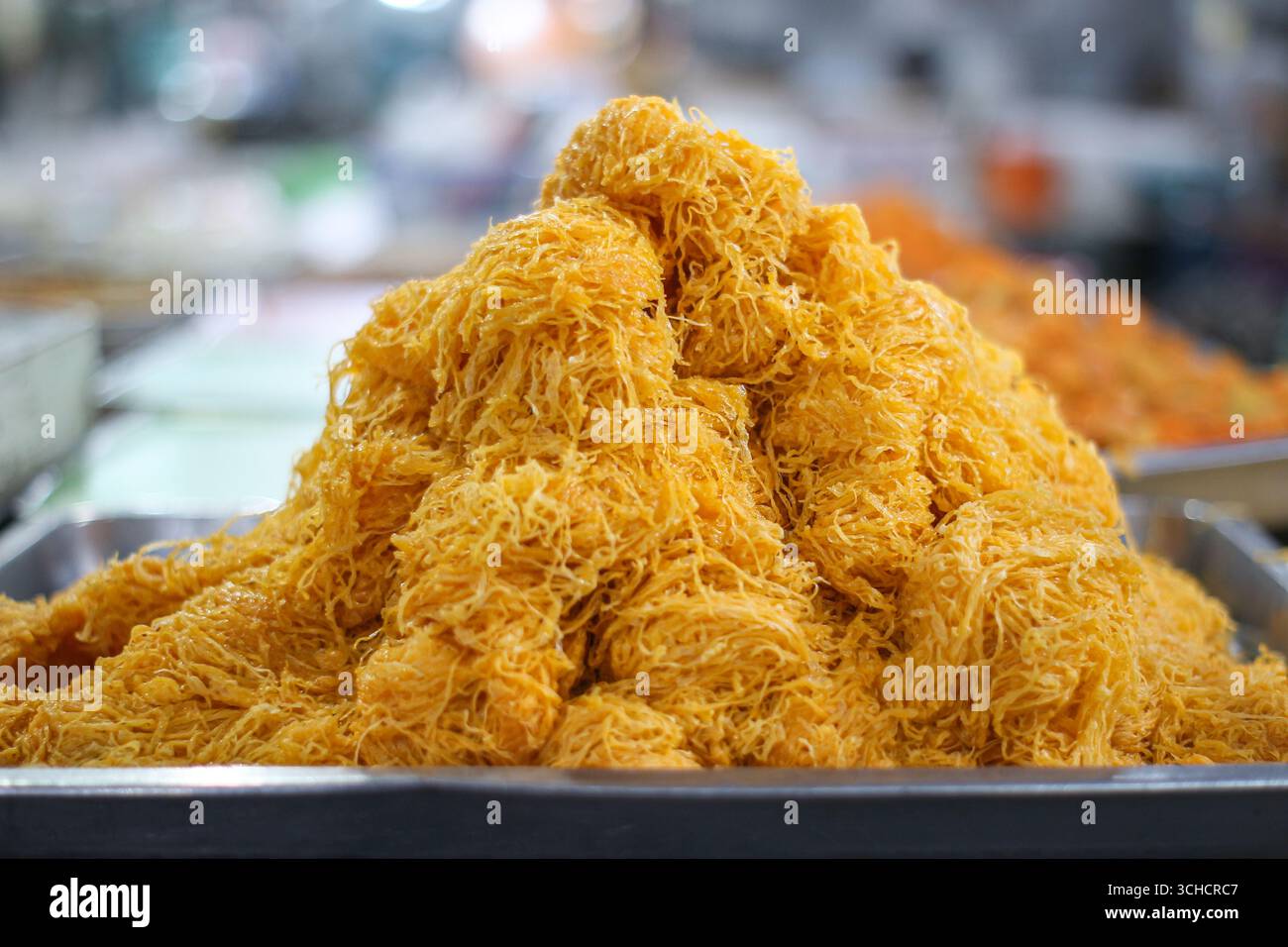 Dessert Golden Foi Thong, delicati fili di tuorlo d'uovo impilati in alto su un vassoio Tradizionale dolce thailandese spesso visto nel cibo di strada e nei mercati festivi. Foto Stock
