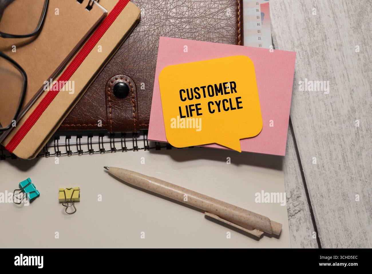 Sul blocco note per scrivere il testo Customer Life Cycle, lente di ingrandimento, grafici e occhiali Foto Stock