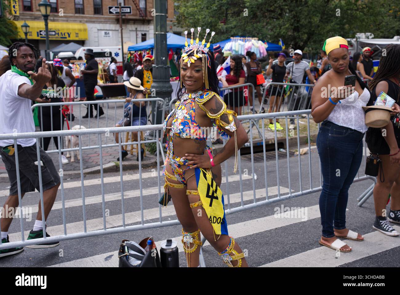Una donna con un costume colorato e ornato posa in un festival di strada, con una folla sullo sfondo. Foto Stock