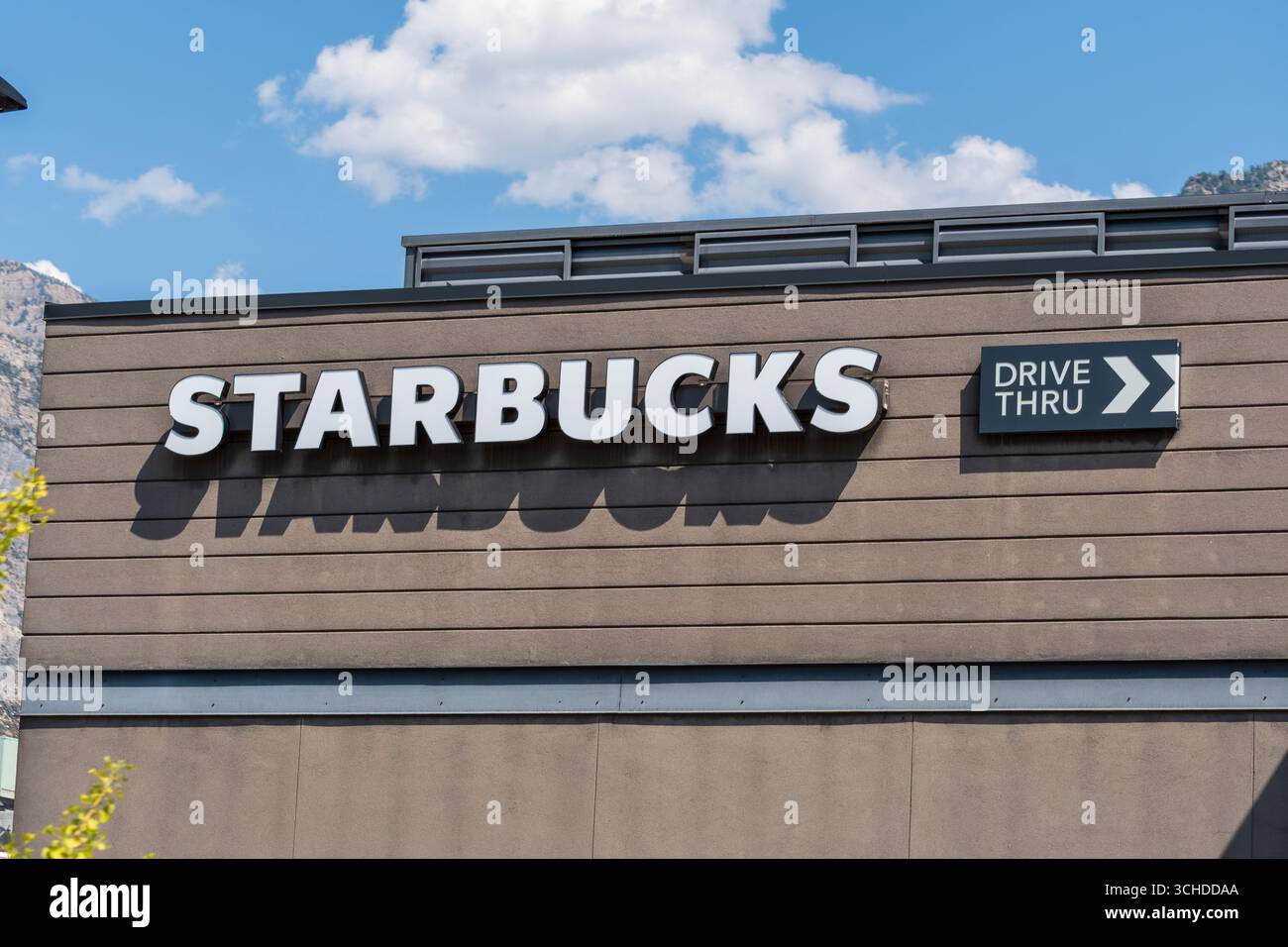 Provo, Utah, Stati Uniti d'America - 1 settembre 2025: Un moderno punto vendita Starbucks presenta una segnaletica audace e linee architettoniche pulite sotto cieli parzialmente nuvolosi. Foto Stock