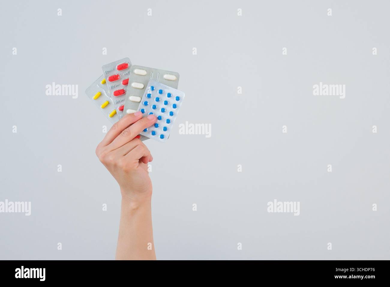 La mano di una donna tiene le pillole su uno sfondo grigio. Foto Stock