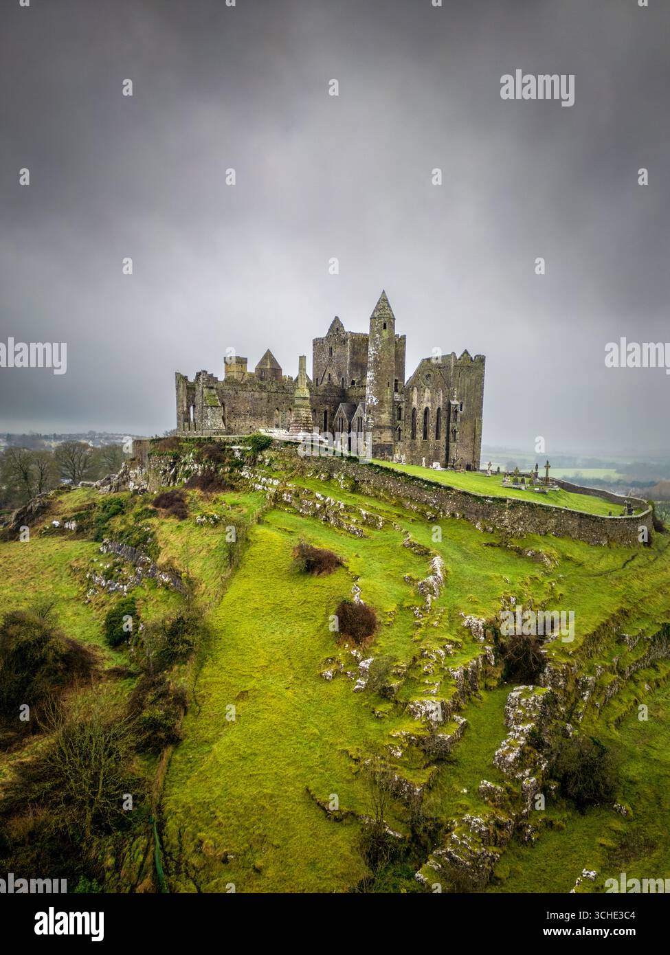 Vista aerea della sagoma rocciosa della Rocca di Cashel si erge su un cielo lunare, abbracciato da vibranti colline verdi., Cashel, Contea di Tipperary, Irlanda. Foto Stock