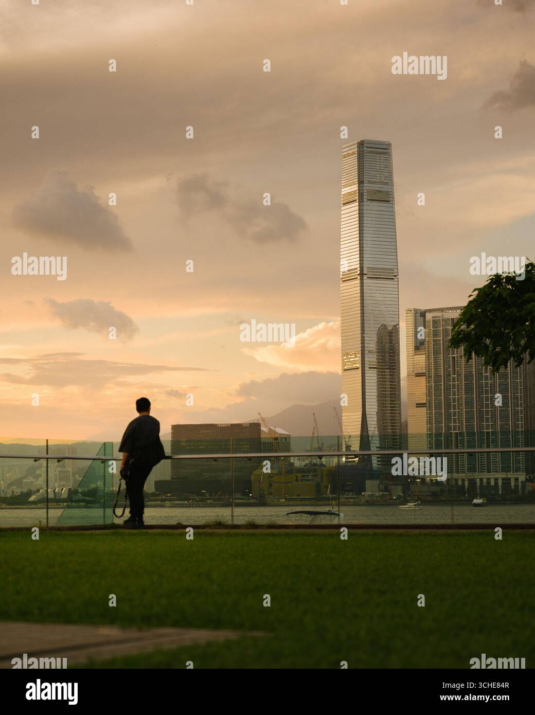 Vista del porto Victoria di Hong Kong al tramonto guardando verso il quartiere di Kowloon con lo skyline della città Foto Stock