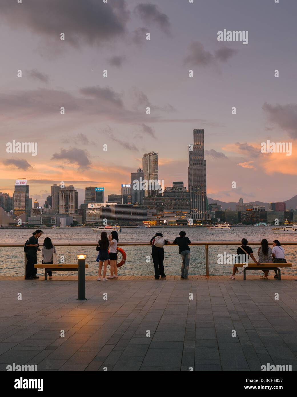 Vista del porto Victoria di Hong Kong al tramonto guardando verso il quartiere di Kowloon con lo skyline della città Foto Stock