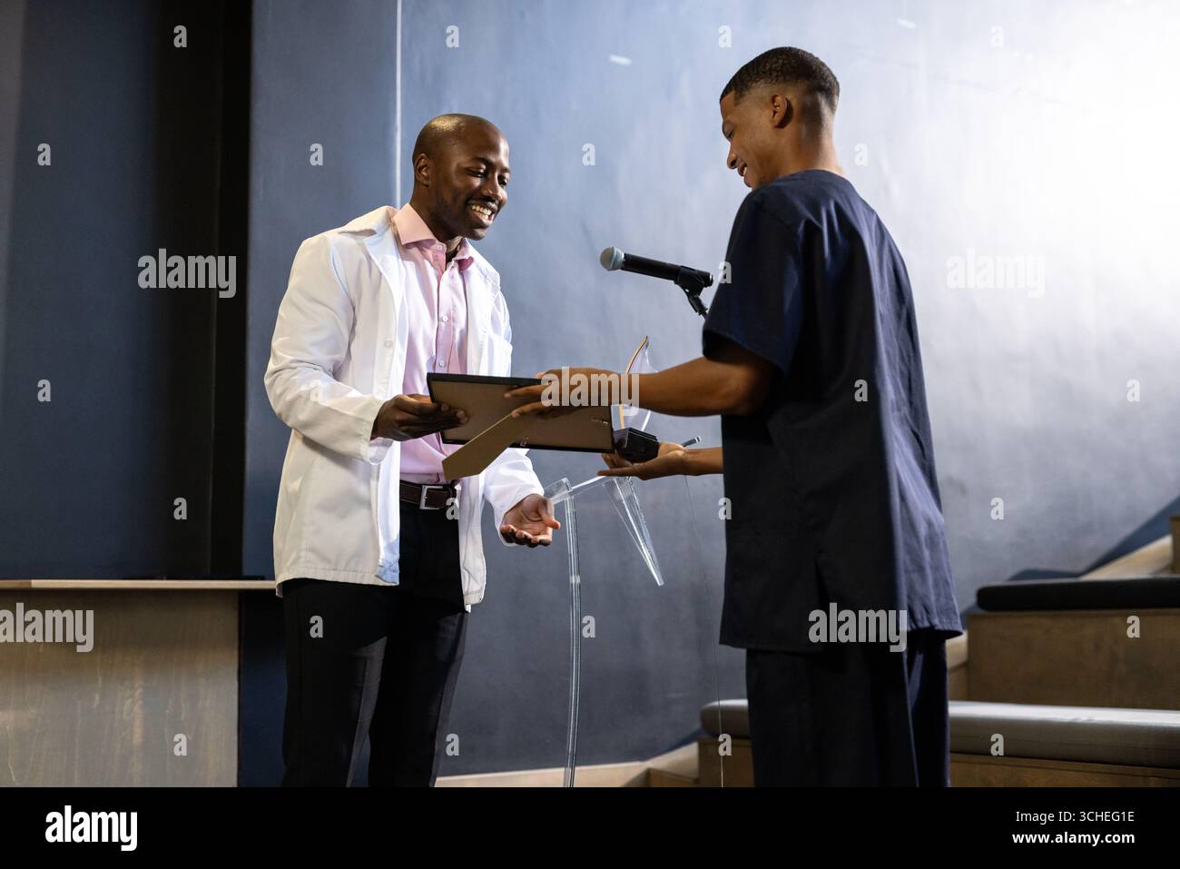 uomo che riceve il premio da un collega sul podio durante la cerimonia, in ufficio, nella sala conferenze Foto Stock