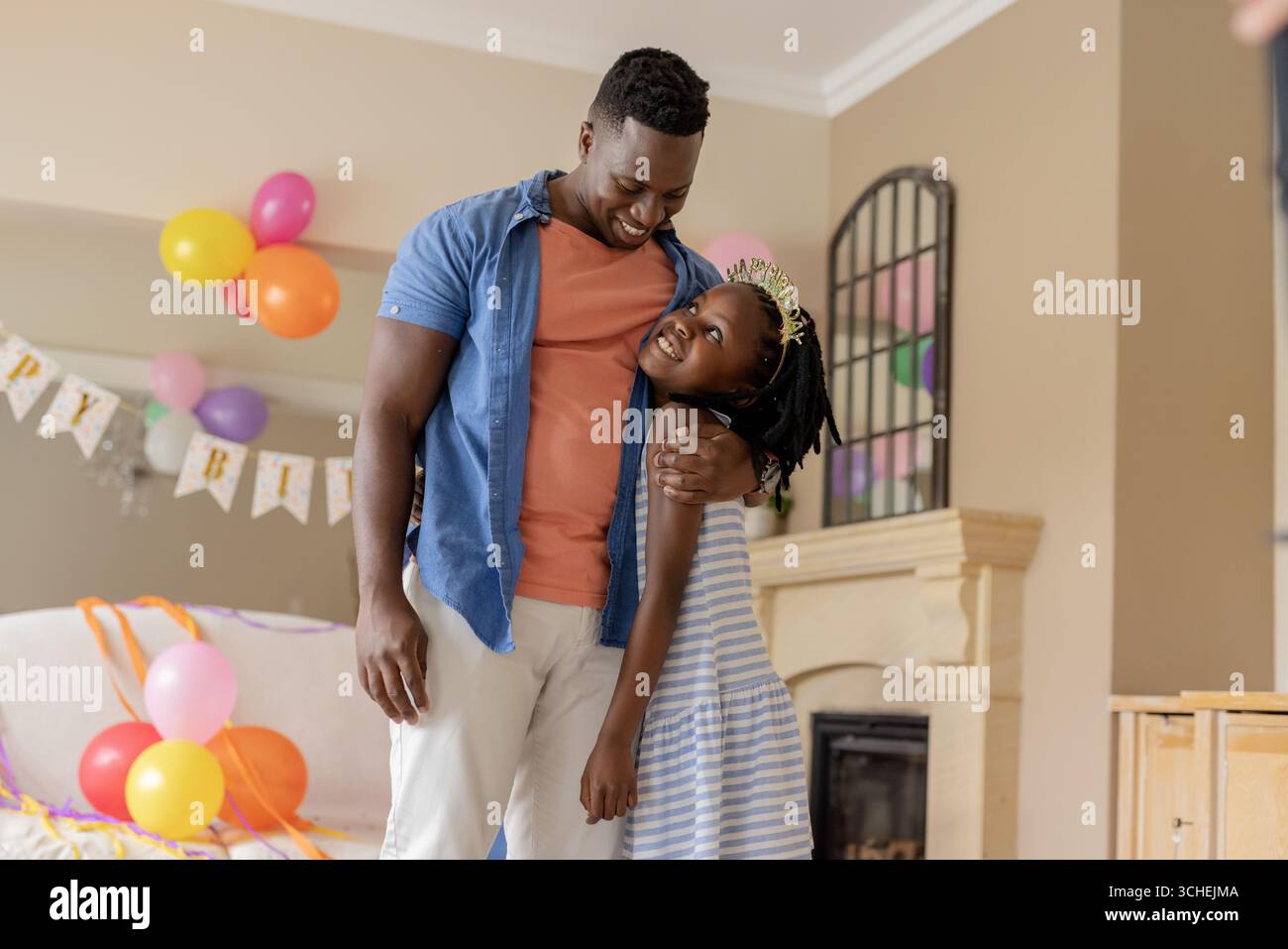 Alla festa, festeggiando il compleanno a casa, padre e figlia afroamericani con palloncini Foto Stock