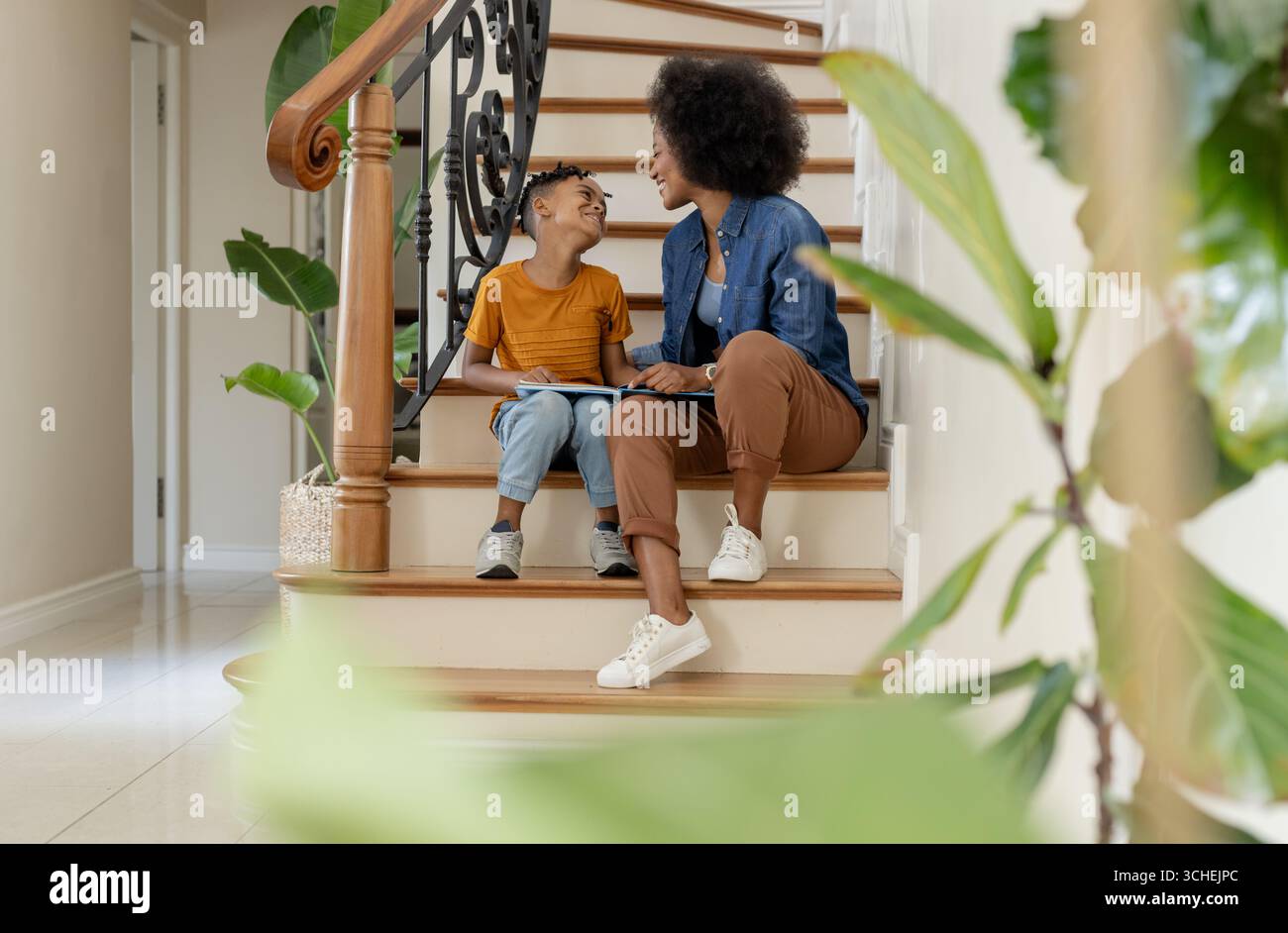 Madre e figlio seduti sulle scale, a leggere libri e a condividere momenti di gioia Foto Stock