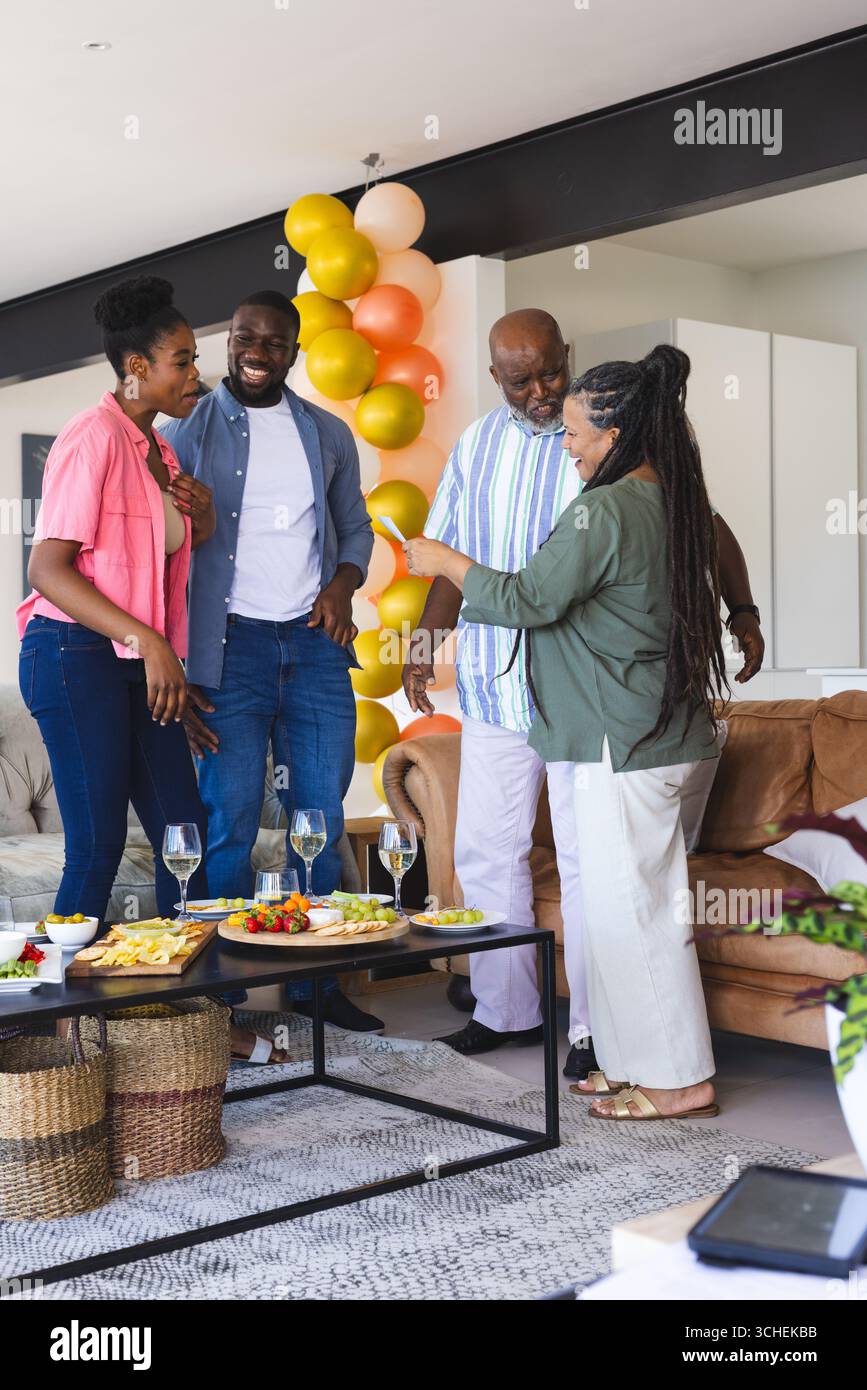 La famiglia festeggia insieme a casa, si diverte a ridere e a conversare con un drink Foto Stock