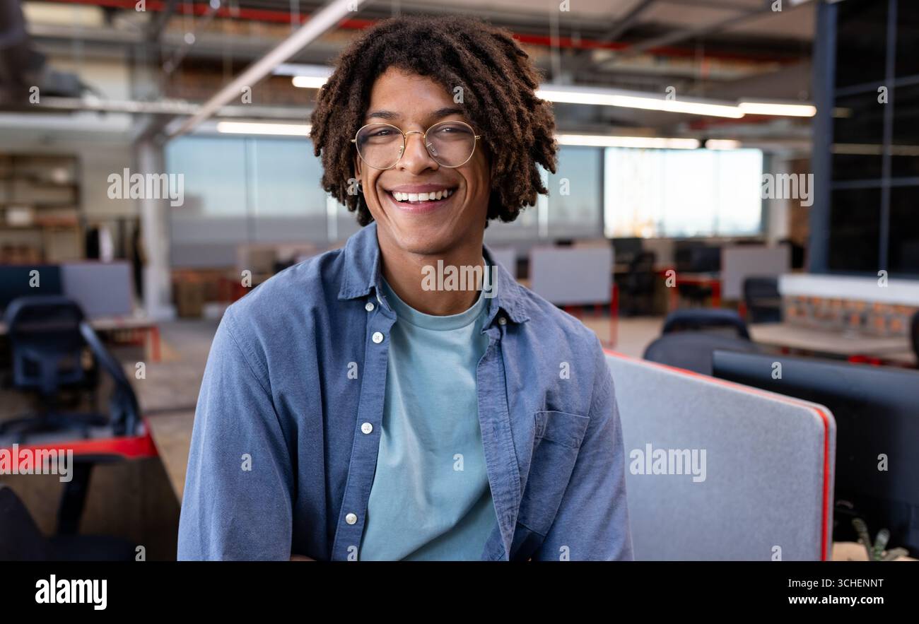 Un giovane sorridente in un ufficio moderno, che gode di un ambiente di lavoro creativo e di uno spazio di copia Foto Stock