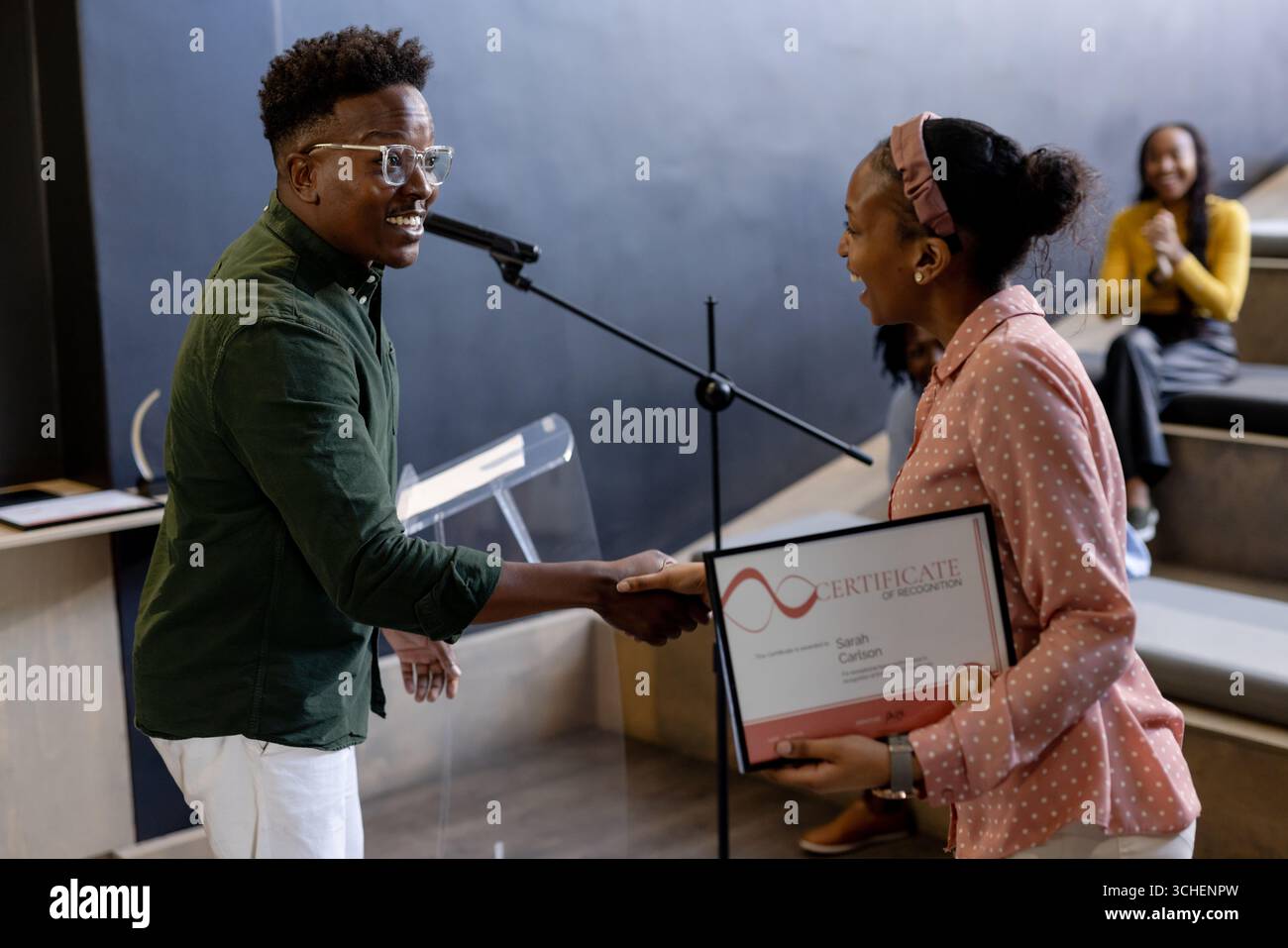 In ufficio, donna sorridente che riceve il certificato sul palco durante la cerimonia di premiazione aziendale Foto Stock
