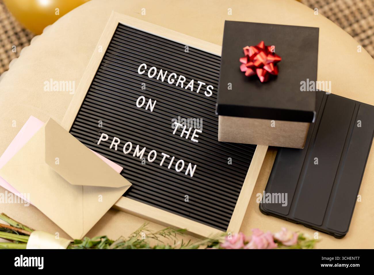 Promozione per festeggiare, tabellone con scatola regalo e fiori sul tavolo, in ufficio Foto Stock