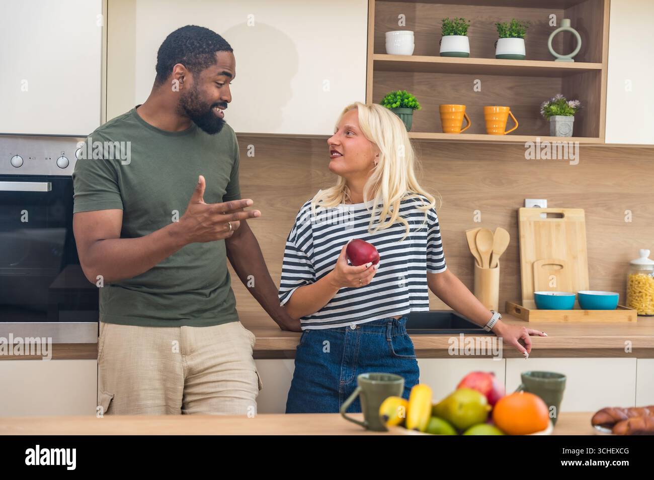 Giovane coppia felice che si gode del tempo libero a casa, in piedi in cucina, a fare colazione, alla routine mattutina. Persone adorabili amano le attività del fine settimana Foto Stock