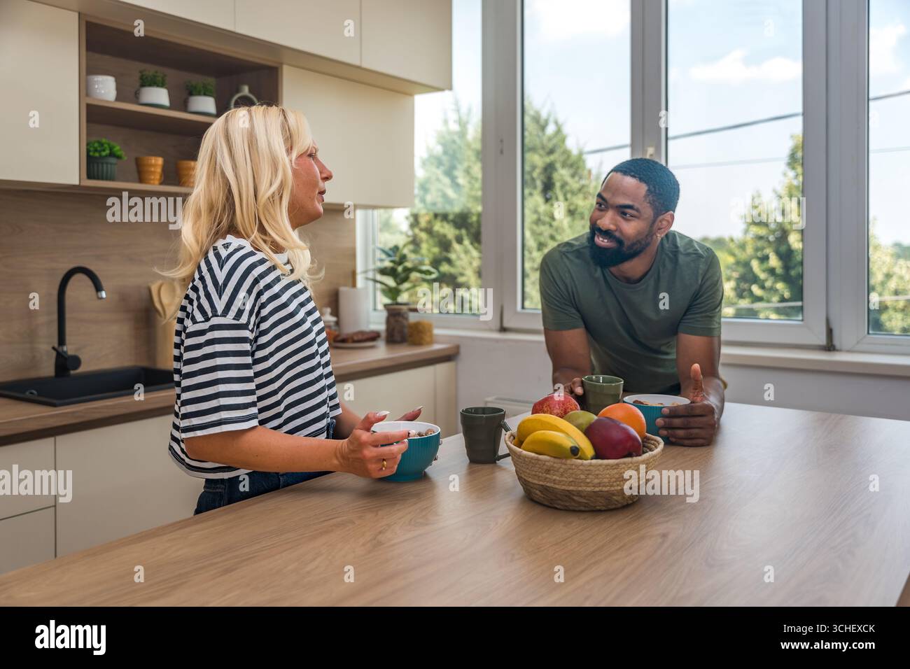 Giovane coppia felice che si gode del tempo libero a casa, in piedi in cucina, a fare colazione, alla routine mattutina. Persone adorabili amano le attività del fine settimana Foto Stock