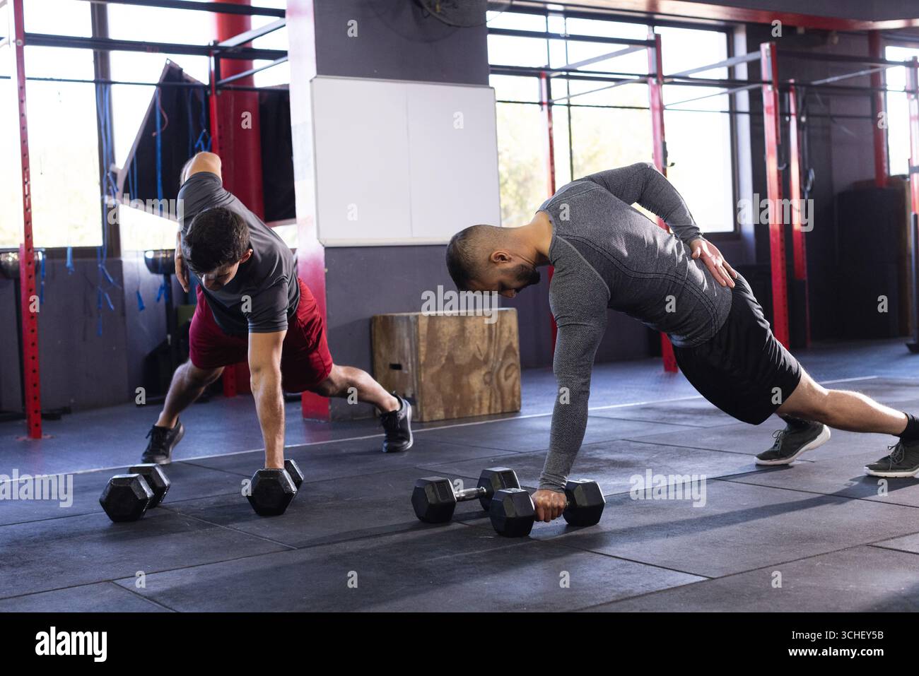 Diversi amici maschili che si allenano eseguendo file di manubri in palestra utilizzando manubri esagonali Foto Stock