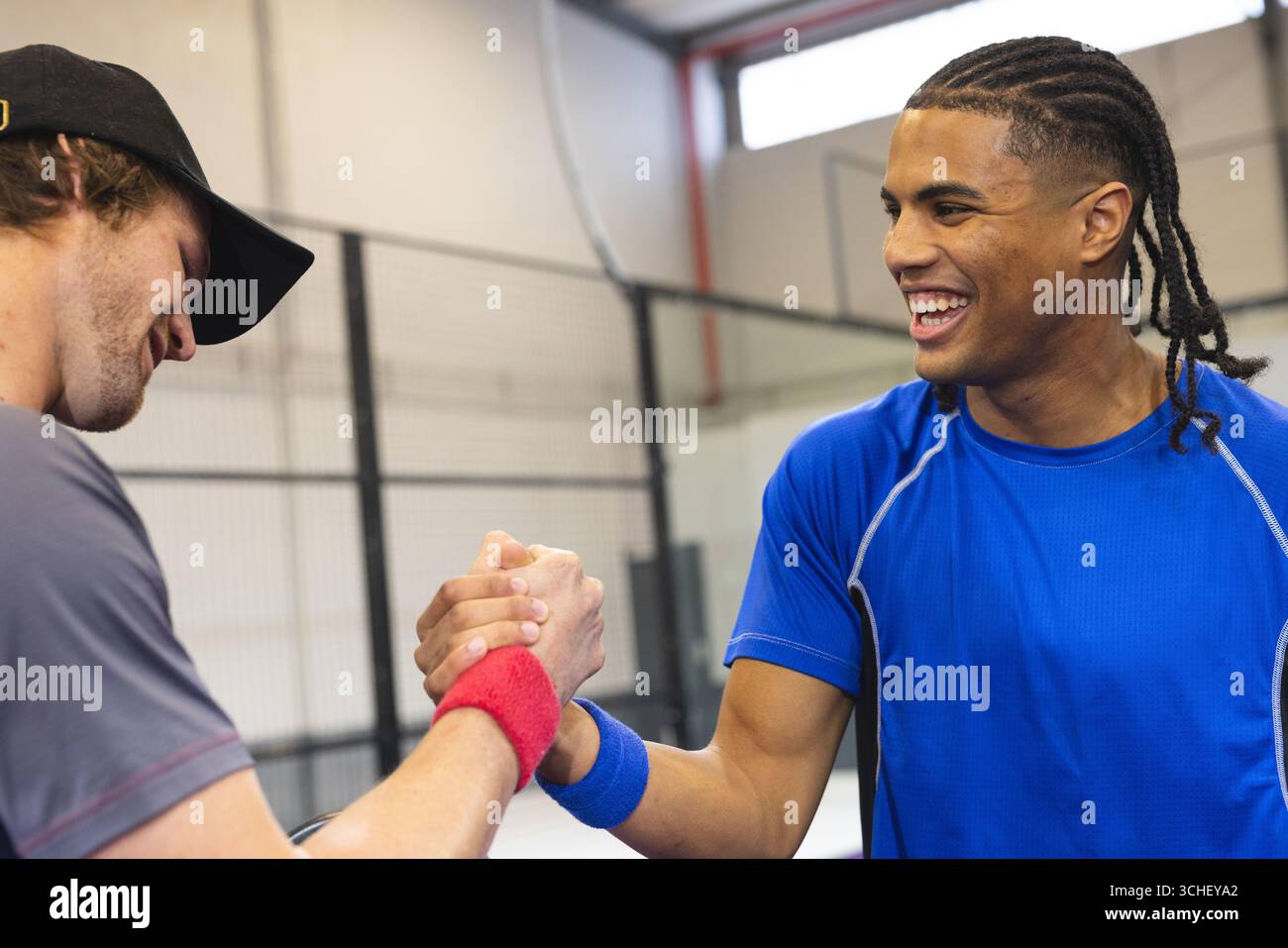 Diversi amici maschili stringono le mani all'interno del campo sportivo con braccialetti e berretto Foto Stock