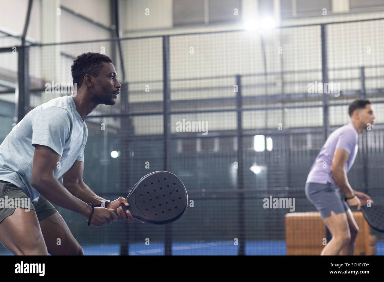 Diversi compagni di squadra maschili in piedi sul campo da paddle tennis con racchette accanto alle pareti in rete, copia di spac Foto Stock