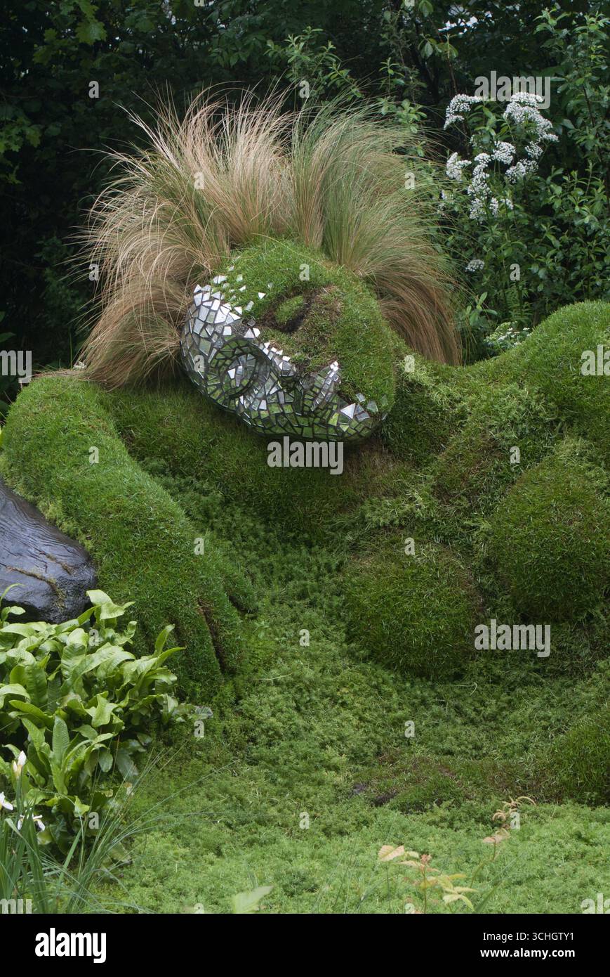 Una grande creatura ricoperta di muschio e erba riposa in una vegetazione vibrante, che mostra il suo design unico e l'ambiente naturale. Foto Stock