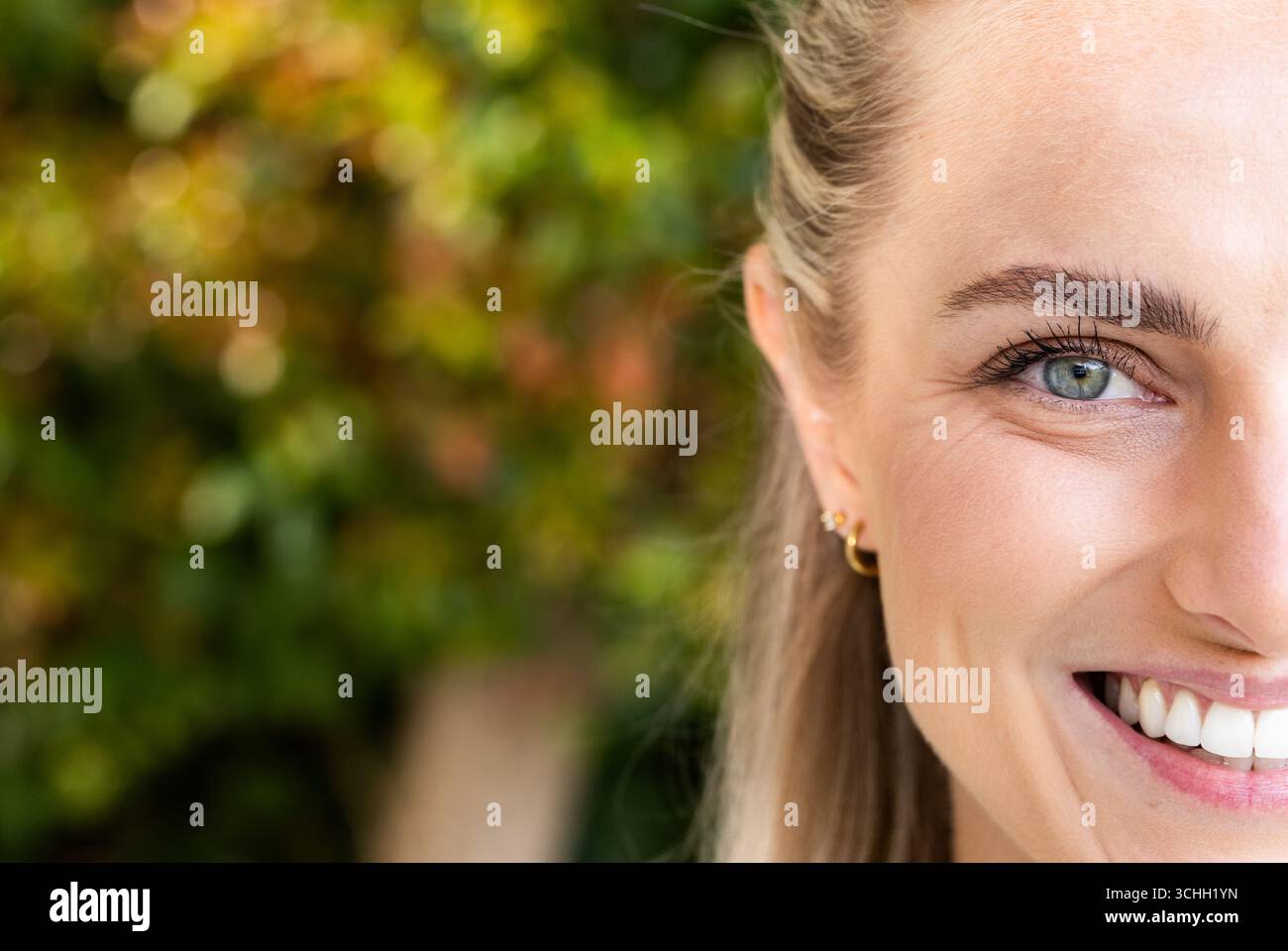 Donna sorridente all'aperto con vegetazione, mostra felicità e bellezza naturale, copia spazio Foto Stock