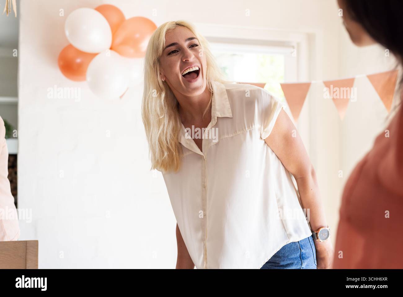 Donna gioiosa che ride alla festa di nozze con palloncini e bunting festivi Foto Stock