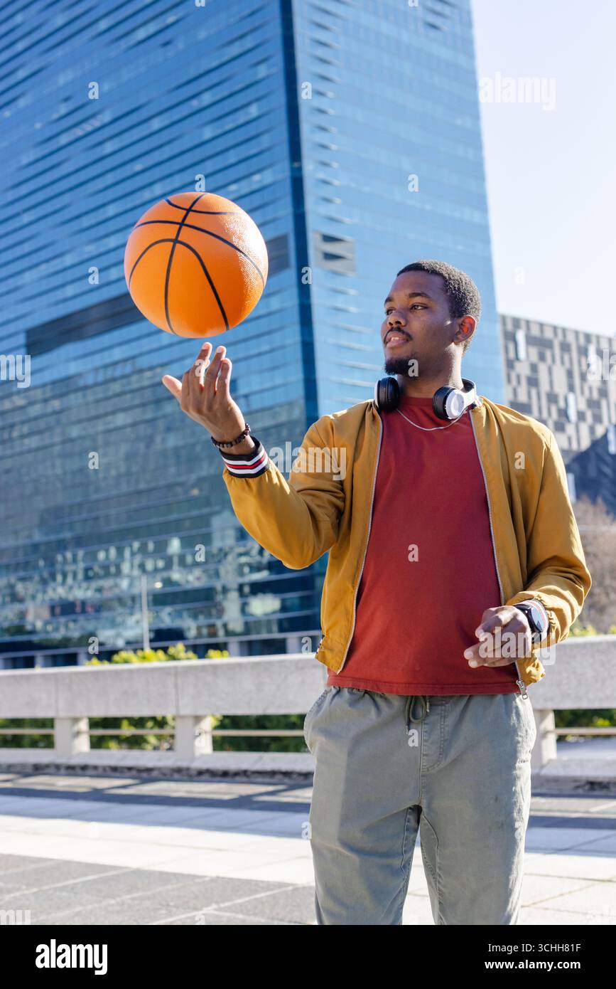 Uomo afro-americano che gioca a basket su plaza con bomber, cuffie, spazio fotocopie Foto Stock