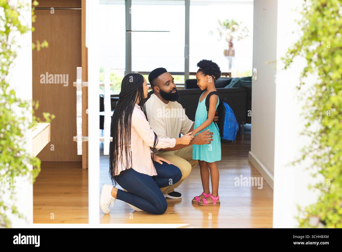 Prepararsi per la scuola, genitori felici che aiutano la figlia con amore e sostegno, a casa Foto Stock