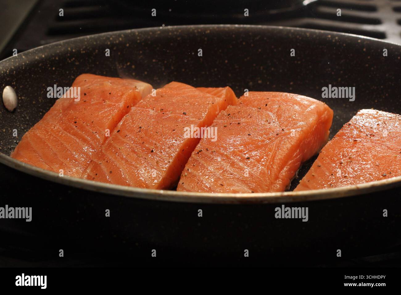 Primo piano di filetti di salmone fresco che si cuocono in padella Foto Stock