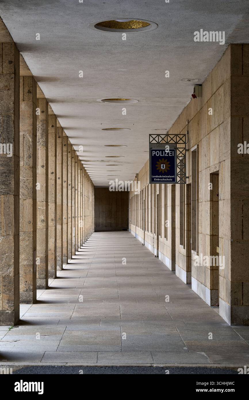 Lungo corridoio interno simmetrico con colonne ripetitive e luce naturale, edificio istituzionale di Berlino, composizione delle linee principali, cornice verticale Foto Stock