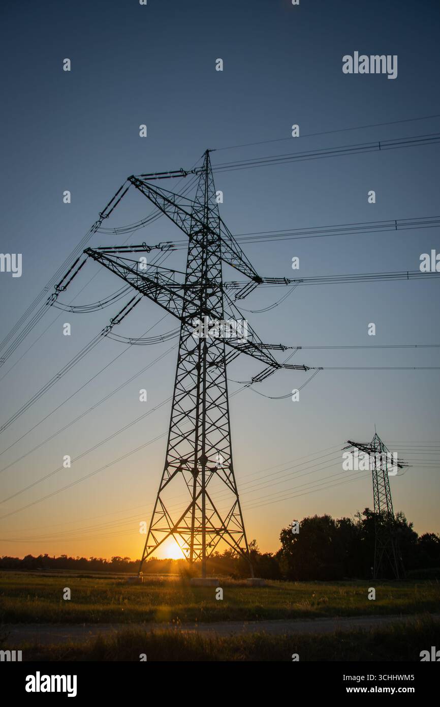 Pilone di trasmissione dell'elettricità ad alta tensione, noto anche come torre di trasmissione, fotografato dal basso al tramonto in Germania. Foto Stock